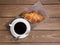 Coffee cup and croissant on wooden background on the table. Perfect breakfast in the morning. Rustic style, top view