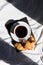 Coffee cup and croissants on the bed in morning sunlight. Trendy still life with interesting shadow.