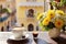 A coffee cup and flowers on a table beside a balcony at sunrise