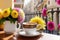 A coffee cup and flowers on a table beside a balcony at sunrise