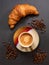 Coffee cup with french croissant and coffee beans on grey slate background. Top view