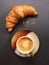 Coffee cup with french croissant on grey slate background. Top view