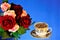 Coffee in a Cup natural invigorating delicious drink and a bouquet of roses for a joyful mood, on a bright blue background
