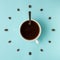 Coffee cup and roasted beans arranged as clock face on blue background, top view. Coffee time symbol. Interesting idea energy and