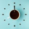 Coffee cup and roasted beans arranged as clock face on blue background, top view. Coffee time symbol. Interesting idea energy and