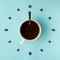 Coffee cup and roasted beans arranged as clock face on blue background, top view. Coffee time symbol. Interesting idea energy and