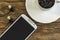 Coffee cup on saucer, smartphone and earphones on wooden surface