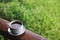 Coffee cup with saucer, on wood panel with defocus green grass lawn background