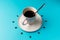 Coffee cup with spoon on saucer and coffee beans against blue background forming clock dia