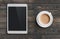 Coffee cup and tablet pc similar to ipad on dark wooden table top view