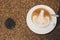 Coffee cup with white foam tulip shape latte art placed on ceramic plate on coffee beans background