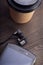 Coffee cup and white smartphone on rustic wooden table. Vintage cafe flat lay composition. Breakfast scene