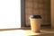 Coffee cup beside window under warm light