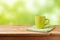 Coffee cup on wooden table over green bokeh background. Mock up for logo design display