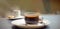 Coffee with date syrup and vegetable milk in glass beaker on gray table. Date syrup trendy. Close-up. Emty space