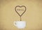 Coffee dripping to a cup from a heart which is made of coffee beans. A symbol of love and care