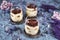 Coffee flavoured layered Italian mascarpone cheese Tiramisu dessert topped with cocoa in glasses