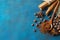Coffee grains scattered on a blue textural background, anise stars, cinnamon sticks and ground coffee in a wooden spoon. Top view