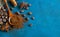Coffee grains scattered on a blue textural background, anise stars, cinnamon sticks and ground coffee in a wooden spoon. Top view
