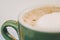 Coffee in green cappuccino ceramic cup with frothy foam, latte capuccino mug closeup. Hot coffee latte in jade color