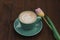 Coffee in a green cup with a pink tulip on a wooden background