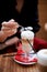 Coffee latte in glass Cup with handle, high foam. Standing on a red napkin. Hands with a spoon