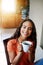 Coffee makes mornings better. a smiling young woman drinking coffee while sitting in a chair at home.