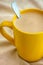 Coffee with milk in yellow mug. Beige napkin background