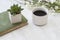 Coffee mug and book with plants on table