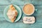 Coffee mug with croissant and notes good morning on turquoise rustic table from above, cozy and tasty breakfast