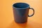Coffee mug grey color on orange background. Hot beverage cup mockup template