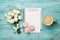Coffee mug with macaron, white flowers and notebook with to do list on blue rustic table from above. Beautiful breakfast. Flat lay