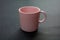 Coffee mug pink color on black background. Hot beverage cup mockup template