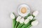 Coffee mug with spring flowers for good morning on gray stone table top view in flat lay style. Breakfast on Mothers or Womens day