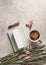 Coffee, notebook, pink flowers and lip gloss on pale grey concrete background. Feminine morning routine. Top view with copy space