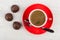 Coffee in red cup, spoon on saucer, chocolate candy