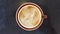 Coffee in rust colored cup on black table