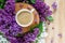 Coffee stands on a wooden hemp surrounded by lilac flowers