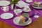 Coffee table setting with white tableware in Christmas style on a table with a purple tablecloth. Merry Christmas concept.