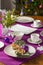 Coffee table setting with white tableware in Christmas style on a table with a purple tablecloth. Merry Christmas concept.