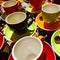 Coffee and teacups in colours orange, yellow, red and black.