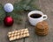 coffee, two linking of cookies and a coniferous branch with scenery