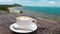 Coffee in White Cup on Plate With Spoon on Wooden Rustic Table, Sea Background with the Palm Tree Movement. Beautiful