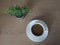 Coffee in a white cup and Trees in stainless steel cans placed on a wooden table