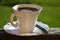 Coffee in white filigree cup with a green spoon