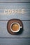 Coffee wooden text word on wooden letters with an espresso coffee served on a white cup on a blue striped textured board