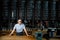 Coffeemaker wearing apron and glasses standing near counter of his cafe with big variety of coffee.