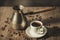 coffeemaker and white cup with coffee with hot steam on a wooden