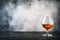 Cognac or brandy in wine glass, gray stone bar counter background, selective focus