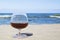 Cognac glass on the background of the sea horizon. Whiskey in a glass on the beach, alcohol and relaxation